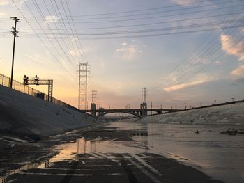 Electricity pylon in city during winter against sky