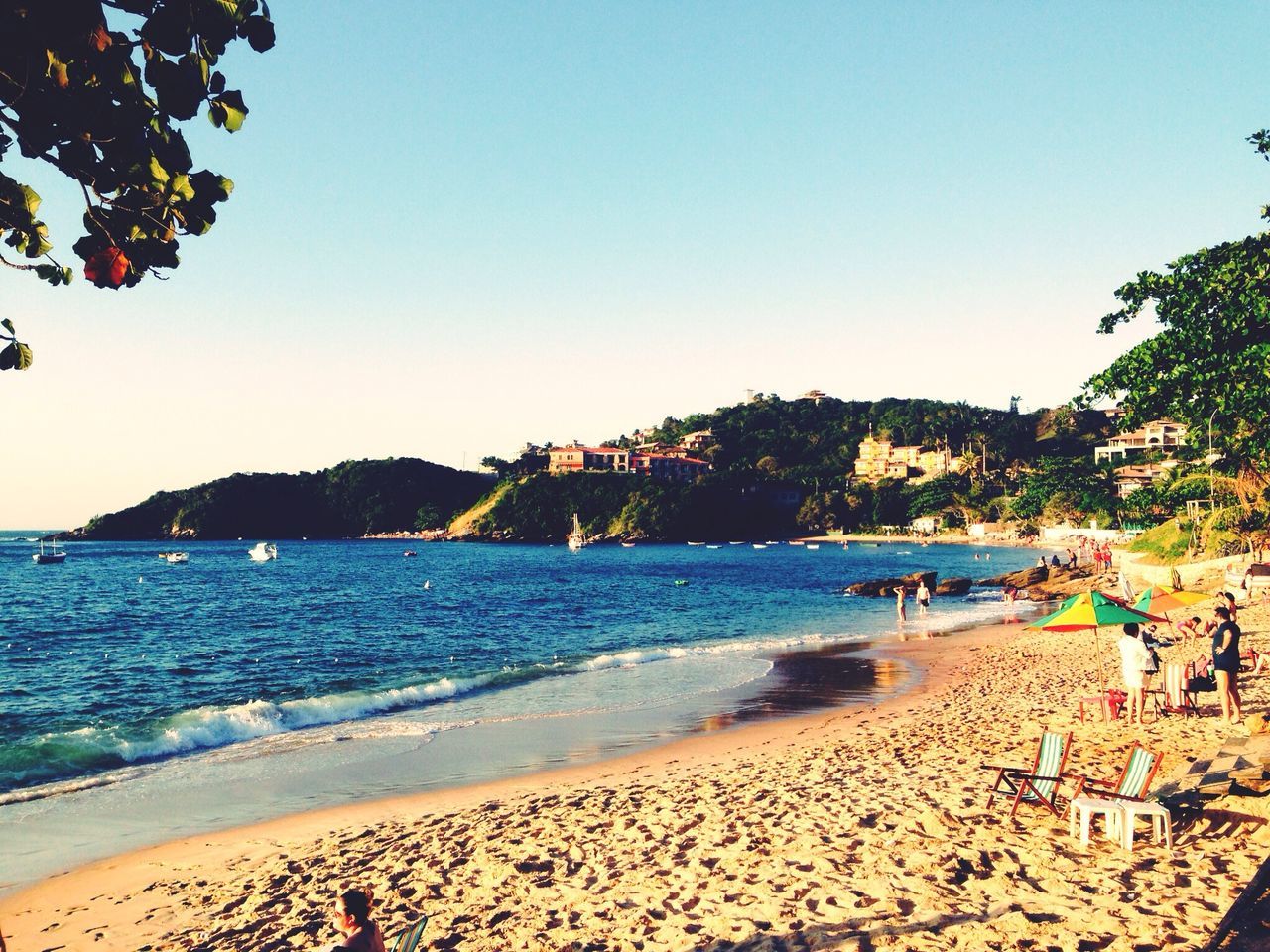 beach, clear sky, water, sea, sand, shore, copy space, scenics, tranquil scene, tranquility, beauty in nature, mountain, blue, tree, nature, large group of people, incidental people, vacations, coastline, tourism