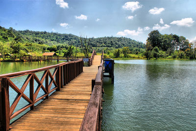 Wooden bridge over lake against sky