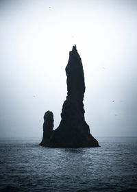 Rock formation in sea against clear sky