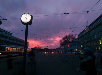 Cars on street in city against sky at sunset