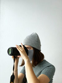 Midsection of woman photographing against wall