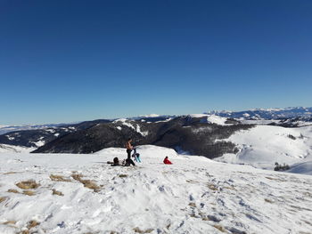 People on snowcapped mountain against clear sky