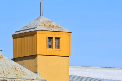 Low angle view of yellow building against clear blue sky