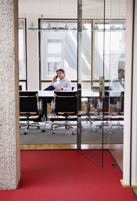 Mature businessman sitting in office talking on cell phone