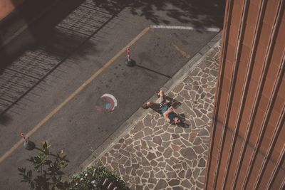 High angle view of man lying on sidewalk