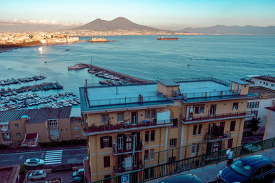 High angle view of city by sea against sky during sunset