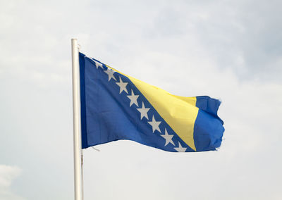 Low angle view of flag against yellow sky