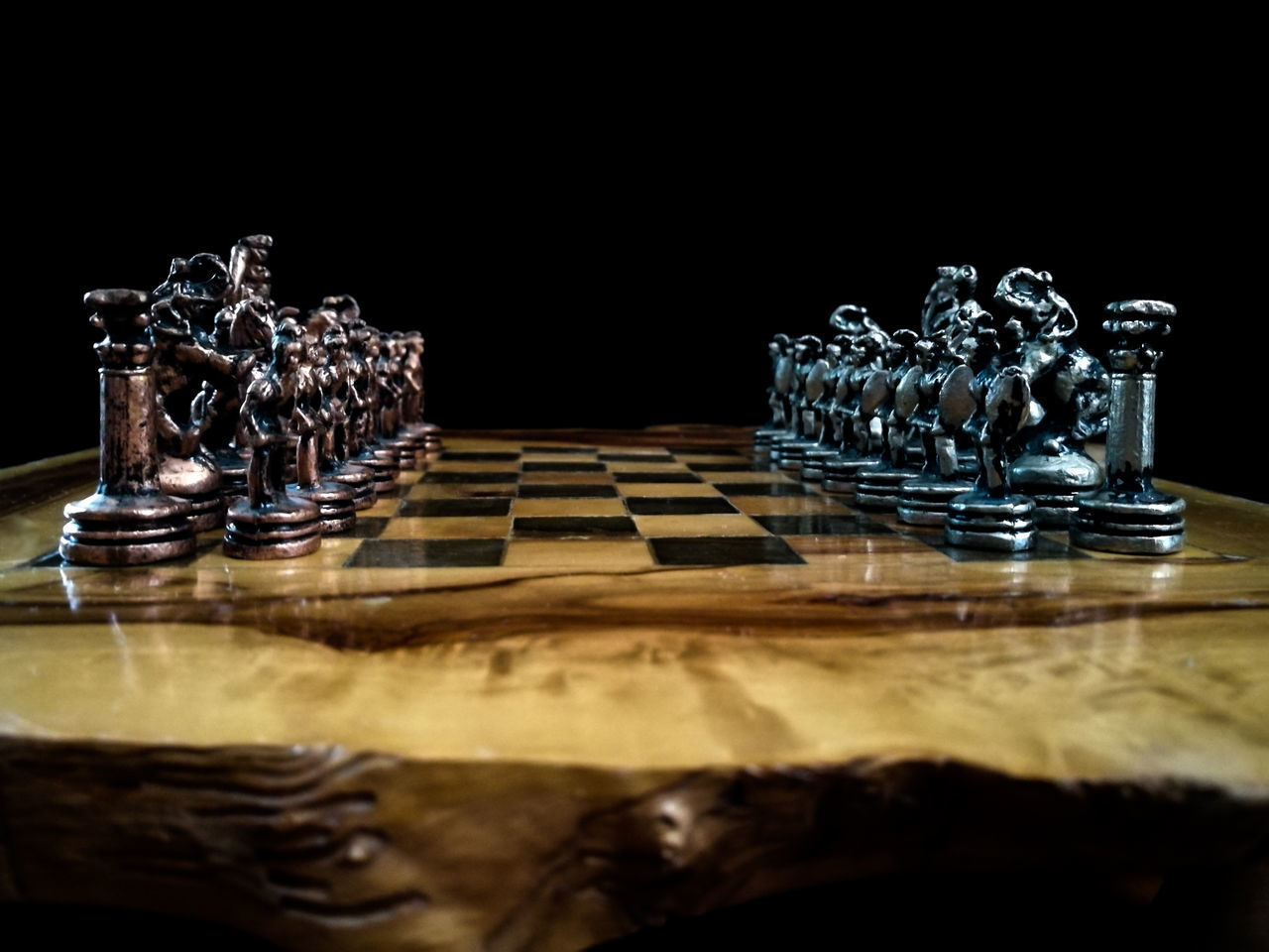 CLOSE-UP OF CHESS PIECES ON TABLE IN THE DARK