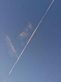 Low angle view of vapor trails against blue sky