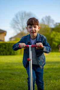 Portrait of boy ridding a scooter on field