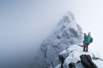 Rear view of people standing on cliff amidst fog