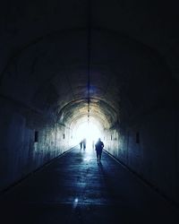 Rear view of silhouette man walking in tunnel