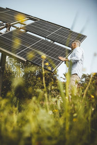 Mature man examining solar panels in garden