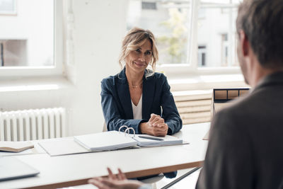 Mature businesswoman talking with client in office