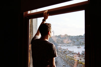 Rear view of man looking through window