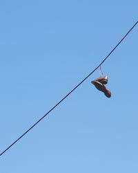 Low angle view of cables against clear blue sky and shoes