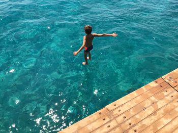 High angle view of shirtless boy jumping in sea