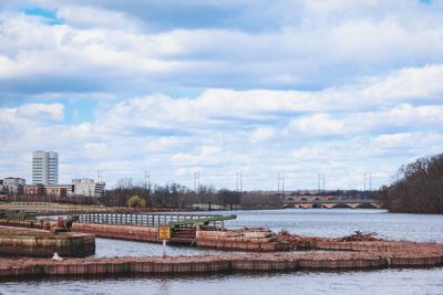 Scenic view of river by city against sky