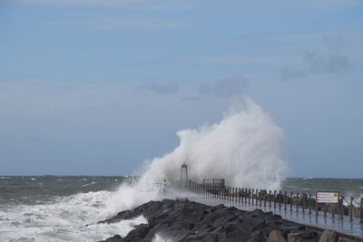 Waves splashing on shore against sky