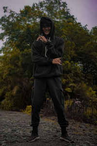 Portrait of young man standing against trees