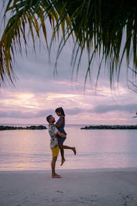 Full length of woman on beach against sky during sunset