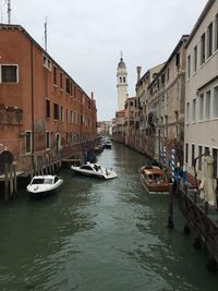 Canal amidst buildings in city against sky