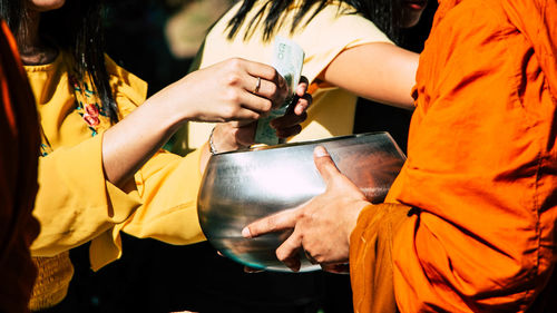 Midsection of woman giving money to monk