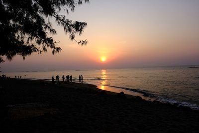 Silhouette people on beach against sky during sunset