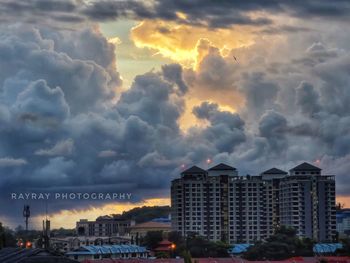 Buildings in city against dramatic sky during sunset