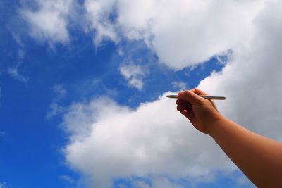 Low angle view of person holding hands against sky