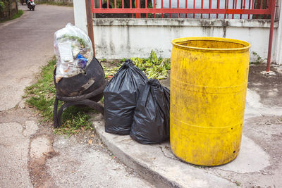 Garbage bin on sidewalk by street in city