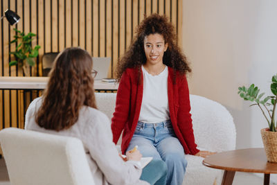 Young woman using mobile phone while sitting on sofa at home