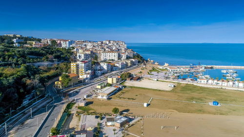High angle view of city by sea against blue sky