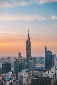 Modern buildings in city against sky during sunset