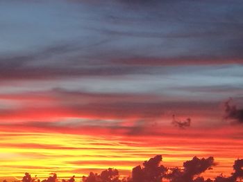 Silhouette buildings against dramatic sky during sunset