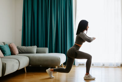 Side view of woman sitting on sofa at home