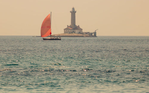 Sailboat in sea against clear sky