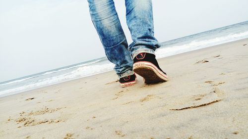 Low section of man standing on beach