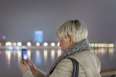 Portrait of woman holding mobile phone at night