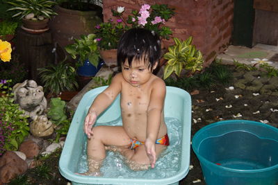 Full length of shirtless young woman sitting in backyard