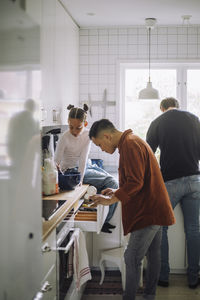 Daughter helping father while preparing food in kitchen at home