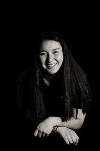 Portrait of a smiling young woman against black background