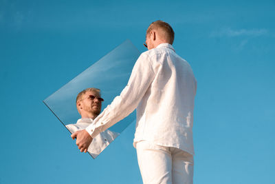 Rear view of woman standing against clear blue sky