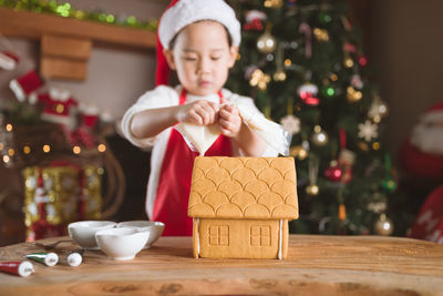 Close-up of gingerbread house on table with girl in background