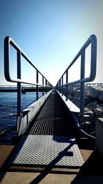 Footbridge over sea against clear sky