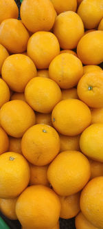View of pile of oranges being sold in market place, top view of sunkist oranges, yellow round fruits