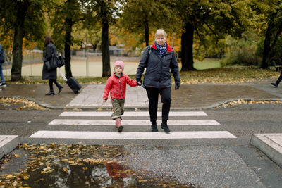 Grandmother walking with grandson on footpath in city