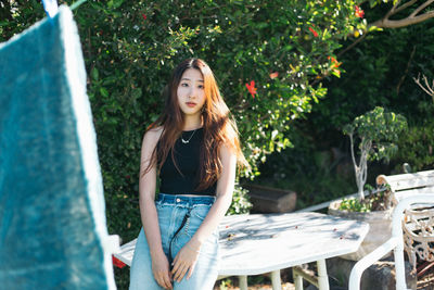 Portrait of young woman against plants in backyard