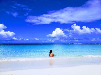 Rear view of woman siting in sea against sky